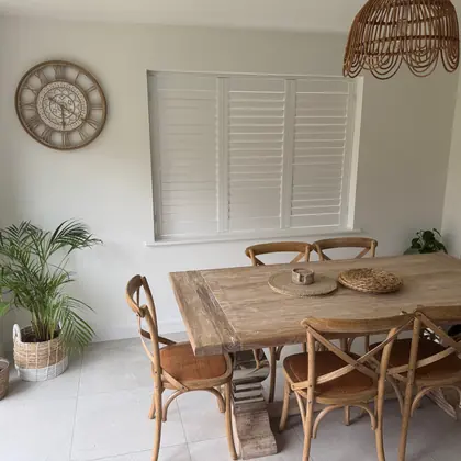 White shutters fitted to a dining room window above a wooden table